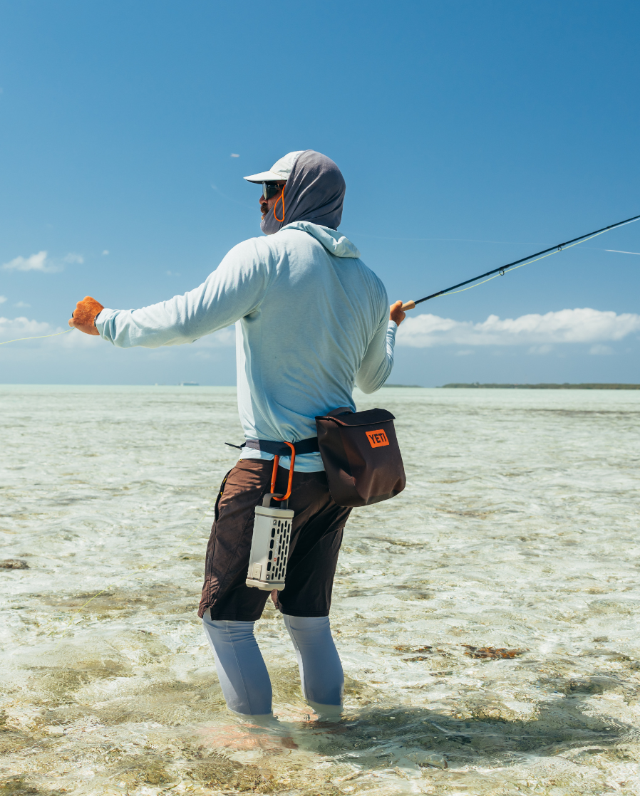 A lifestyle photo of a guy fishing with his Ranger attached to the belt with our Carabiner product