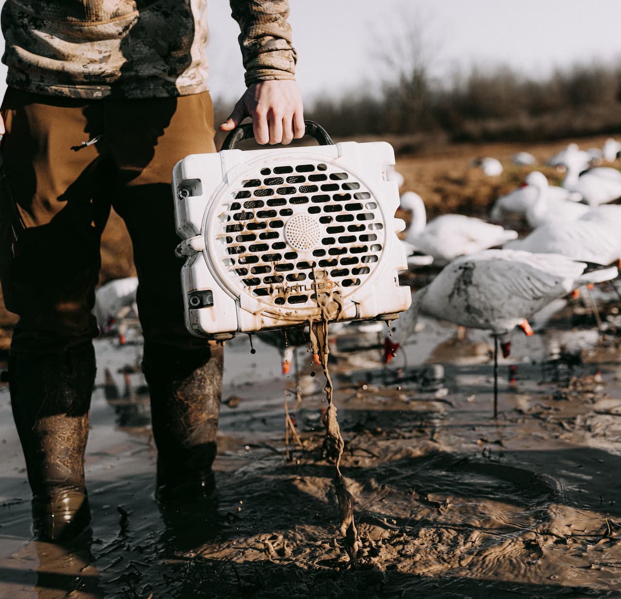 A lifestyle photo from a guy removing Grande speaker in white from mud. #base-color_white