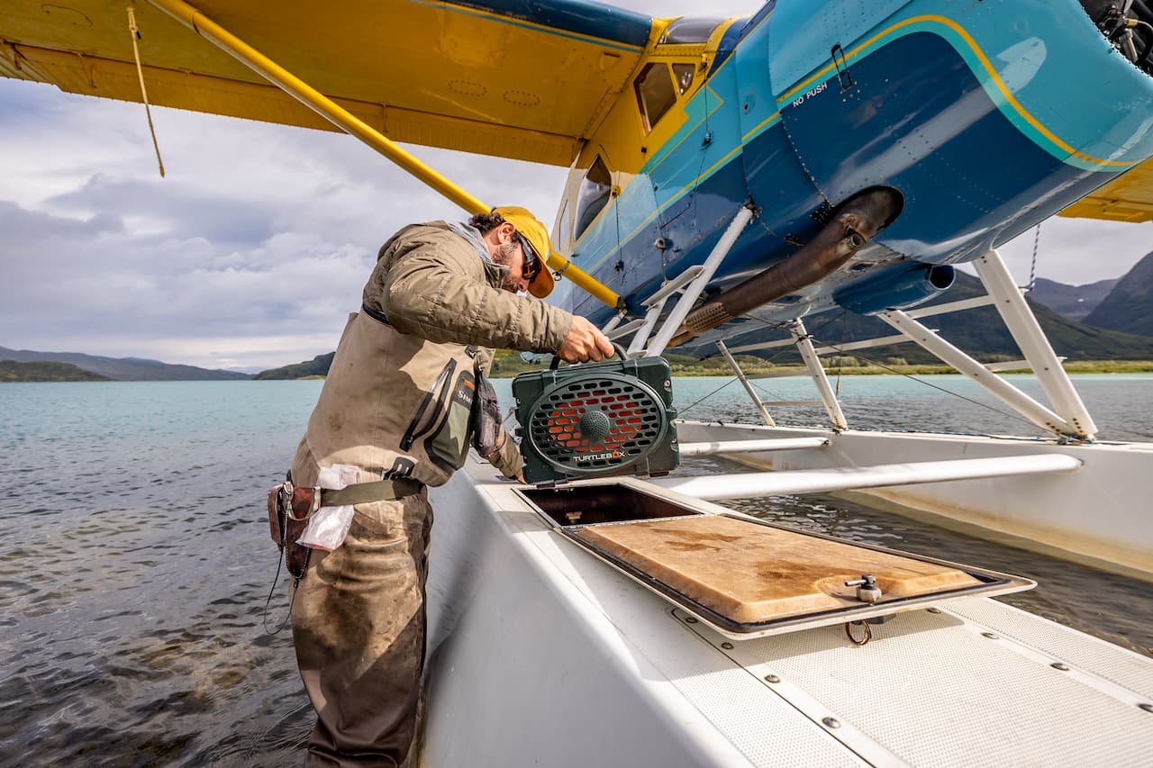 A lifestyle photo showing a man holding a Turtlebox Original Green speaker on his seaplane #speaker-color_green