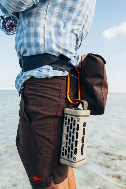A lifestyle photo of a guy fishing with his Ranger speaker in Tan in his belt
